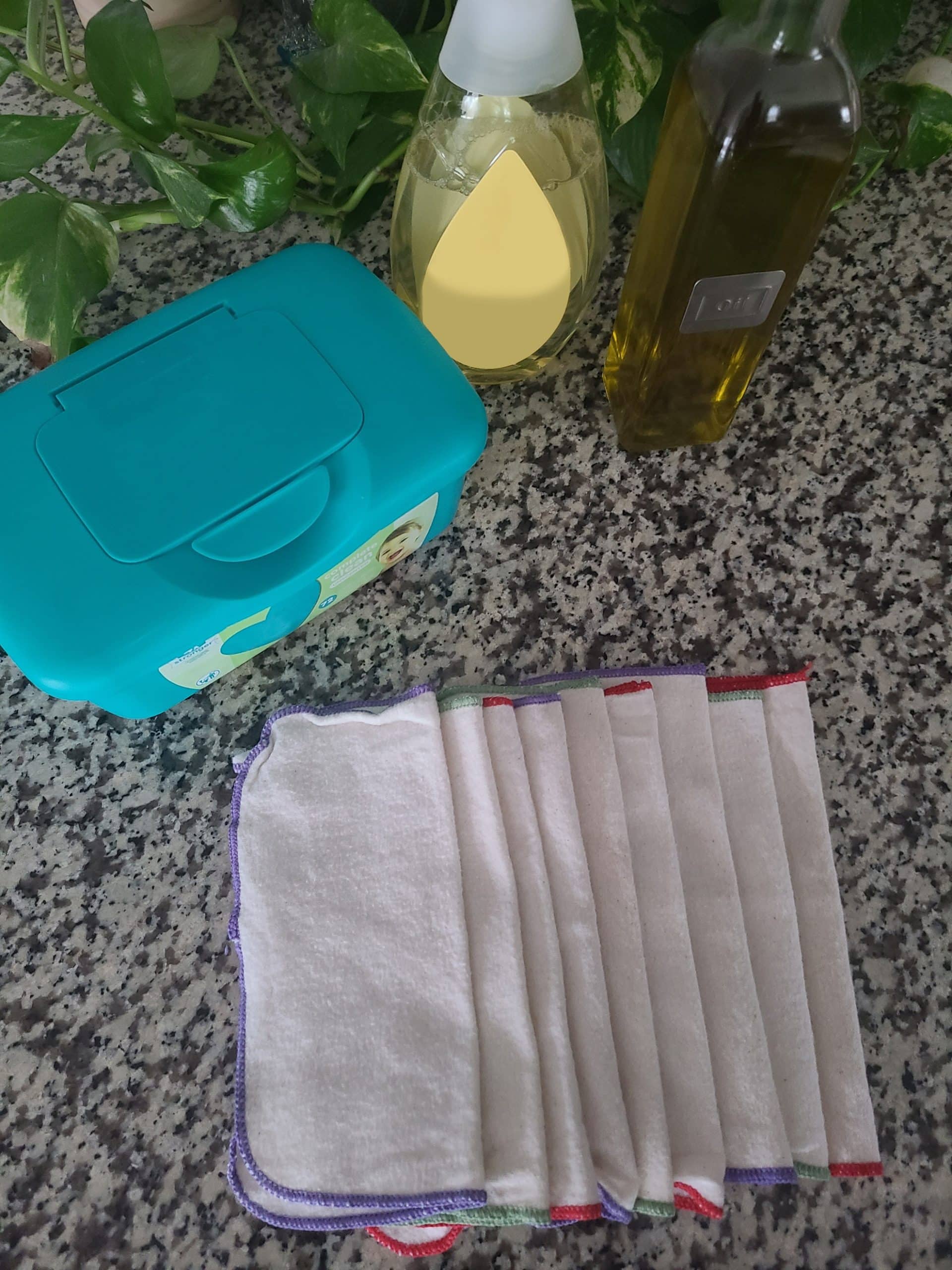 Cloth baby wipes on counter with storage container, baby soap, and olive oil