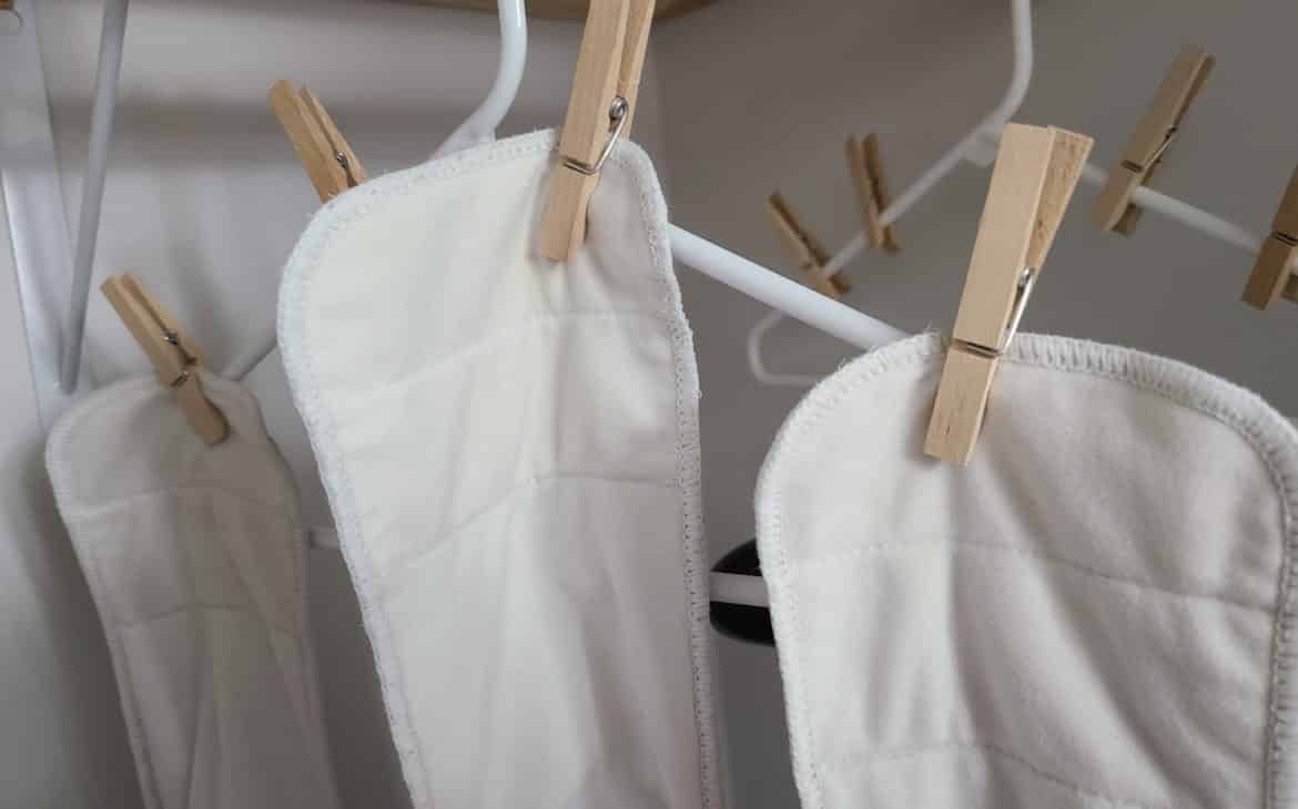 cloth diapers hanging on hangers with wooden clothes pins