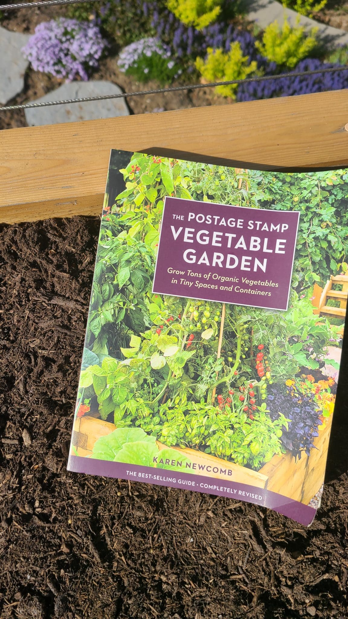 Beginner garden tips are reading books to gain knowledge. Image shows a gardening book on a raised planter box