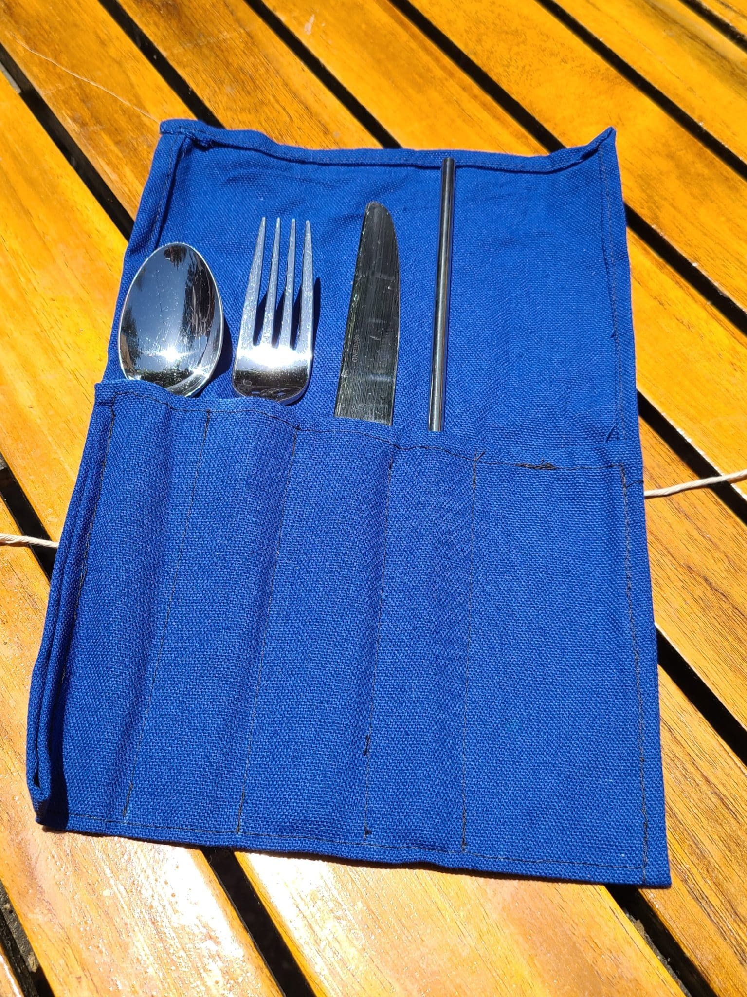 Eco-friendly travel tips for families - a set of your own utensils lying on table in a homemade blue carrying pack.