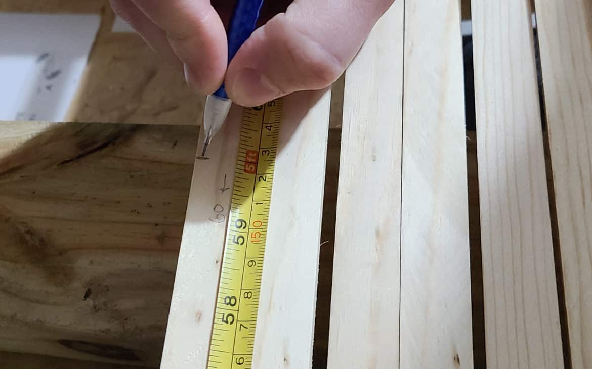 drawing a measurement line on wood strips for door makeover. Labeling which direction is the correct length prior to cutting the strip.