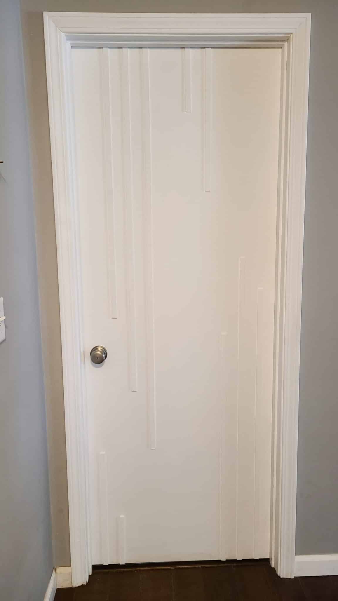 finished interior door makeover project showing white door with wood strip accents