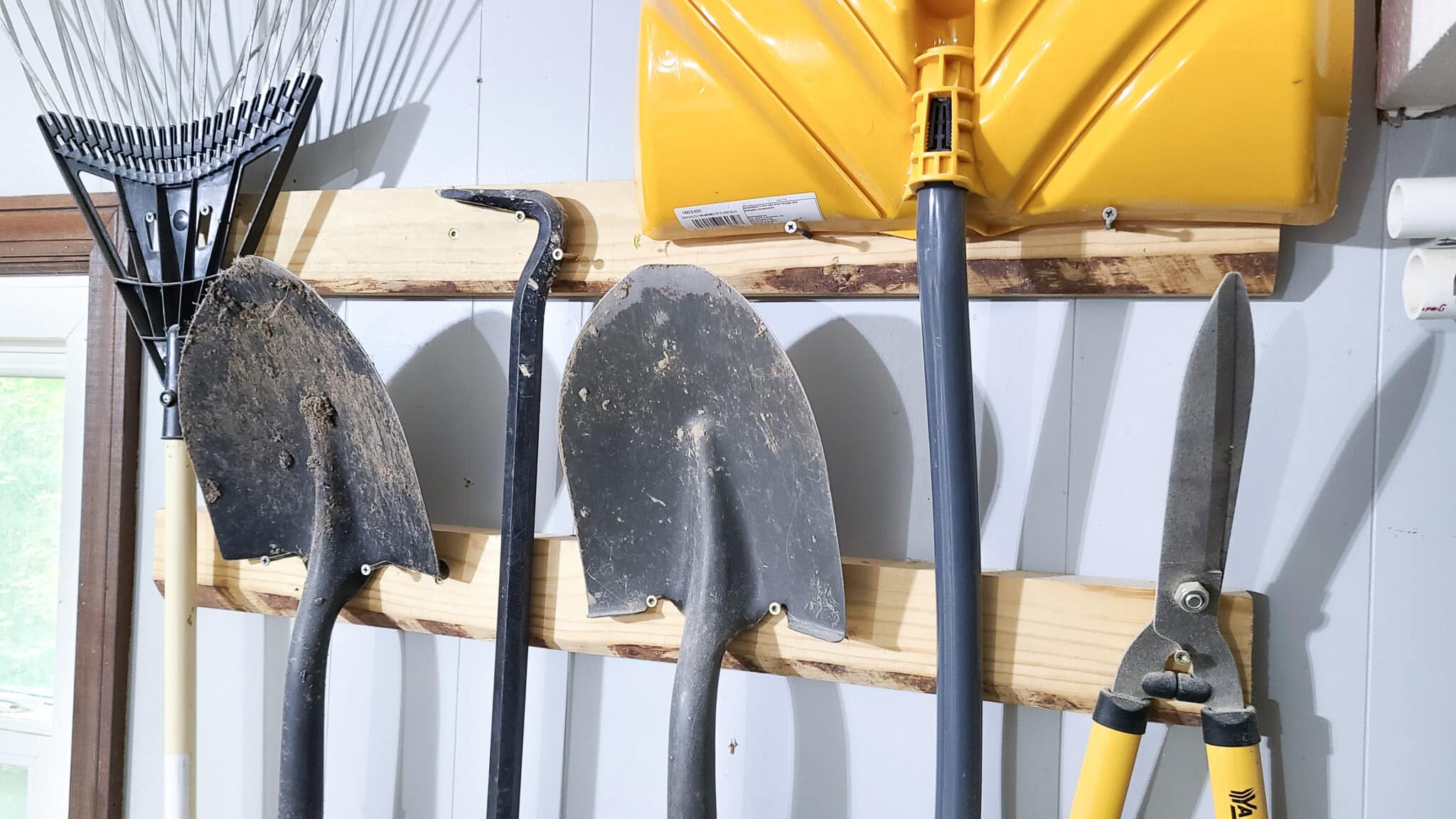 Tools hanging from screws on a wall to help organize a garage or workshop