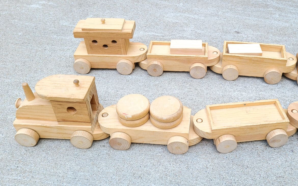 DIY wood train set built and rolling along the ground on concrete