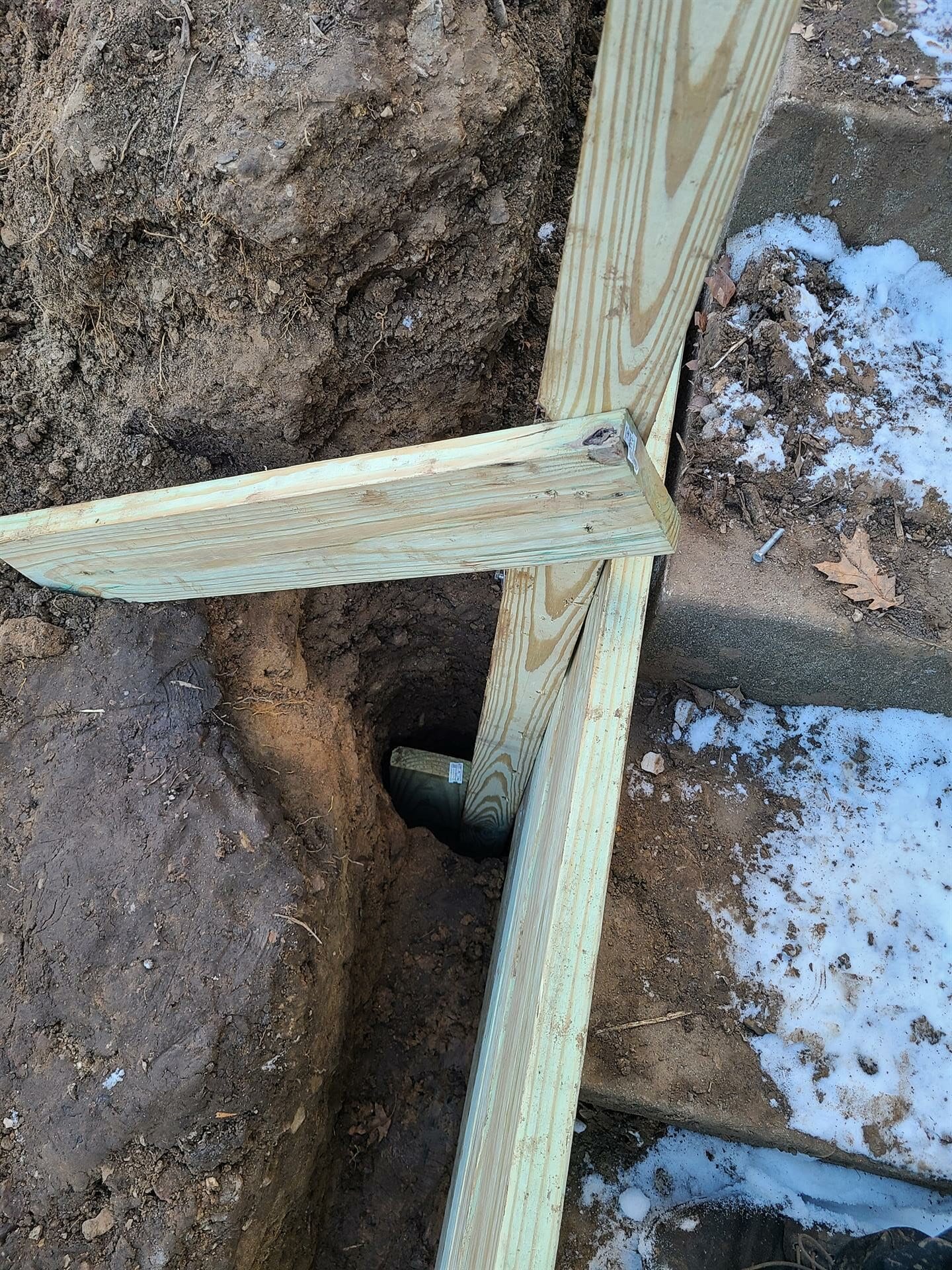 Using scrap wood to brace a wood post for a retaining wall