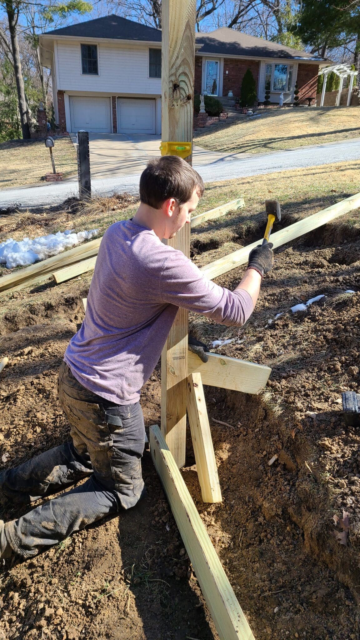 Man adding a brace to support a post for a wood retaining wall