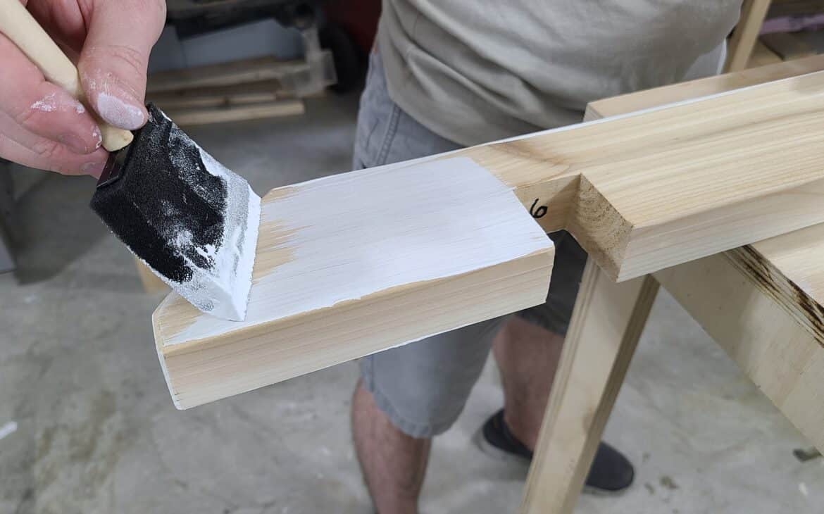 Foam brush applying Rubio's WoodCream to a piece of wood from a trellis